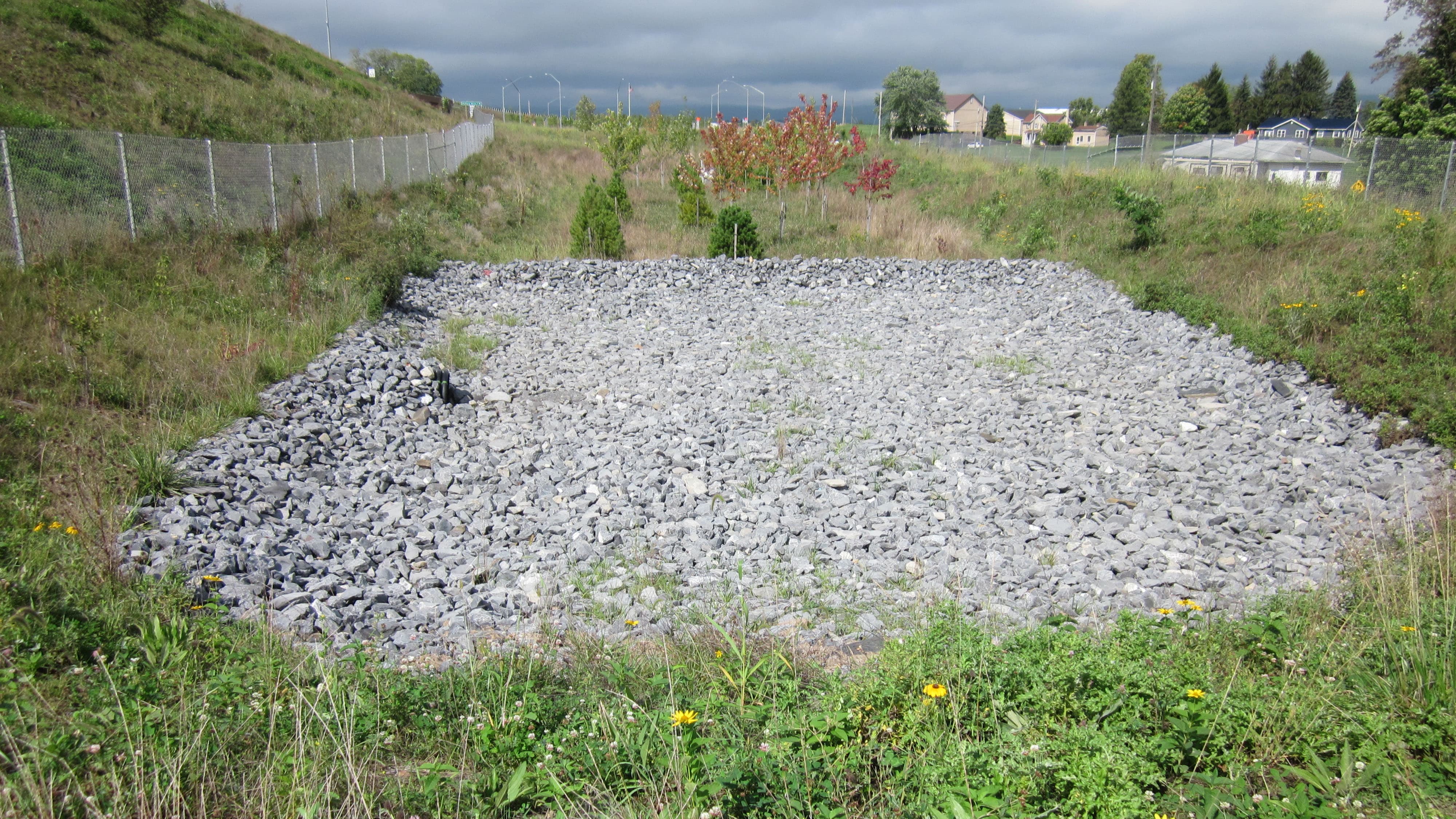 An image of a stormwater runoff area with a large rocky area in the middle to help with drainage